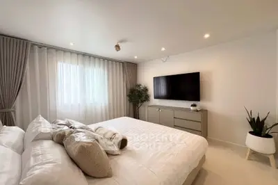 Spacious modern bedroom with elegant decor and large TV