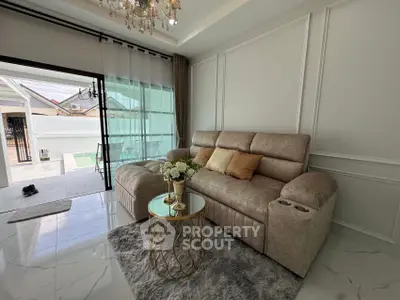 Luxurious living room with elegant sofa and chic decor, opening to a spacious balcony with outdoor view.