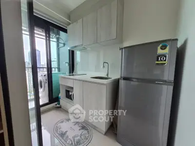 Modern compact kitchen with balcony view, featuring sleek cabinetry and stainless steel appliances.