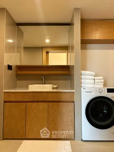 Modern bathroom with wooden cabinetry and washing machine, featuring sleek design and ample storage space.