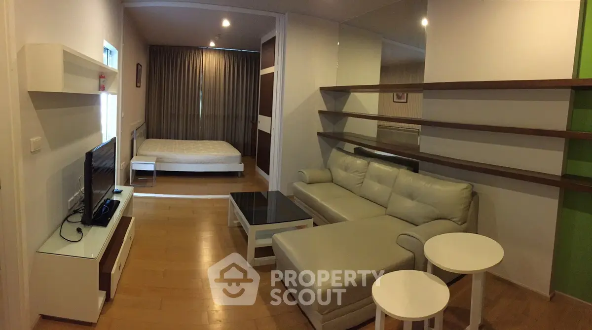 Modern studio apartment with cozy living area and stylish decor, featuring a comfortable sofa and sleek shelving.