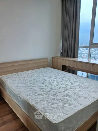 Spacious bedroom with large window offering stunning city views, featuring a modern wooden bed and matching furniture.