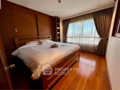 Spacious bedroom with wooden flooring and large window offering natural light.