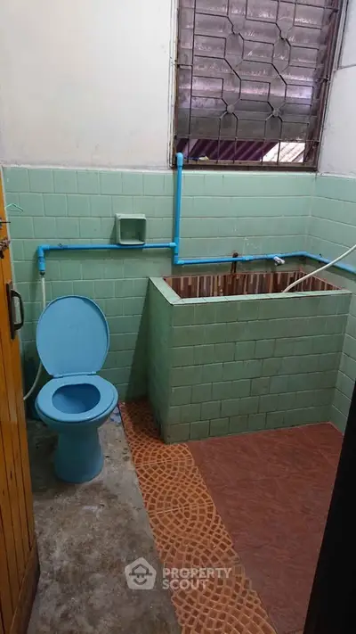 Vintage bathroom with green tiles and unique open water tank design.