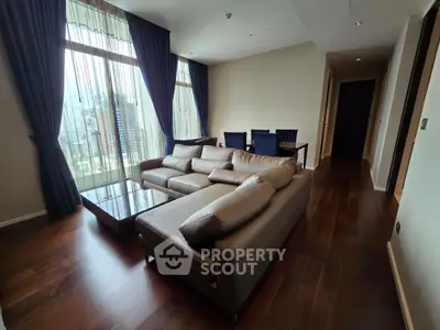 Spacious living room with elegant sofa and city view through large windows.