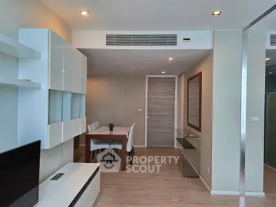 Modern living room with sleek furniture and dining area, featuring elegant wood flooring and contemporary design.