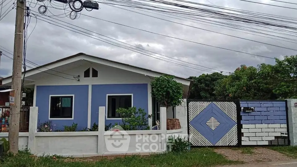 Charming blue single-story house with a fenced yard and decorative gate, perfect for cozy living.