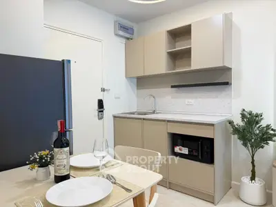 Modern kitchen with sleek cabinetry and dining setup in a cozy apartment.