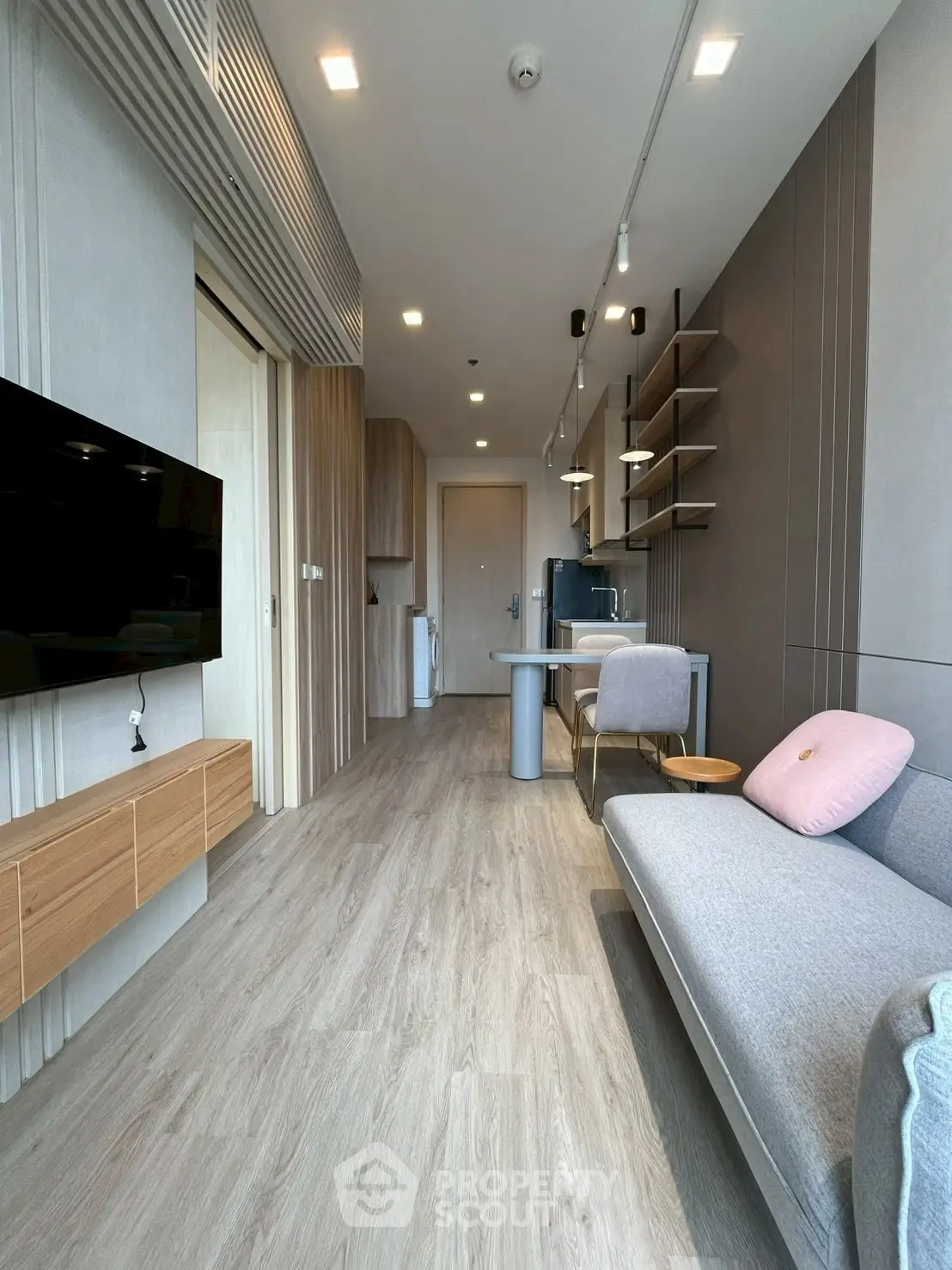Modern living room with sleek design, featuring a cozy sofa, wall-mounted TV, and stylish open kitchen.