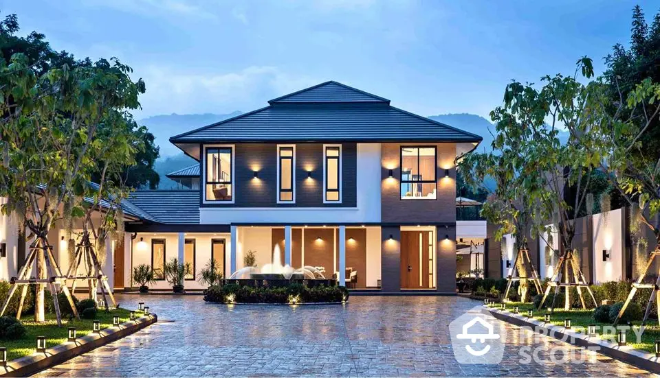 Luxurious modern two-story home with elegant lighting and spacious driveway, surrounded by lush greenery.