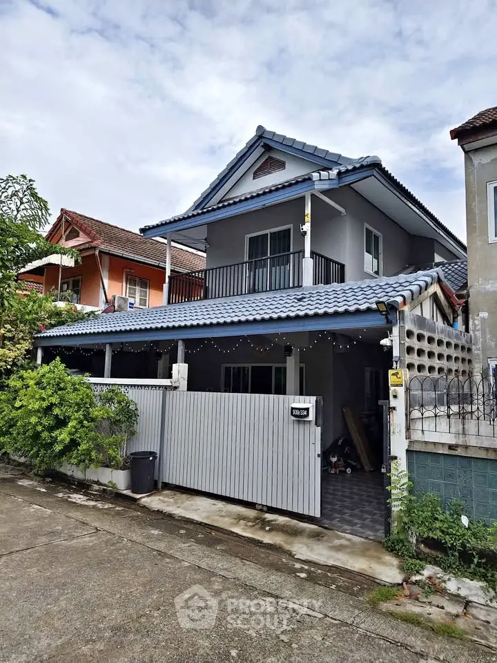 Charming two-story house with blue-tiled roof and spacious balcony in a serene neighborhood.