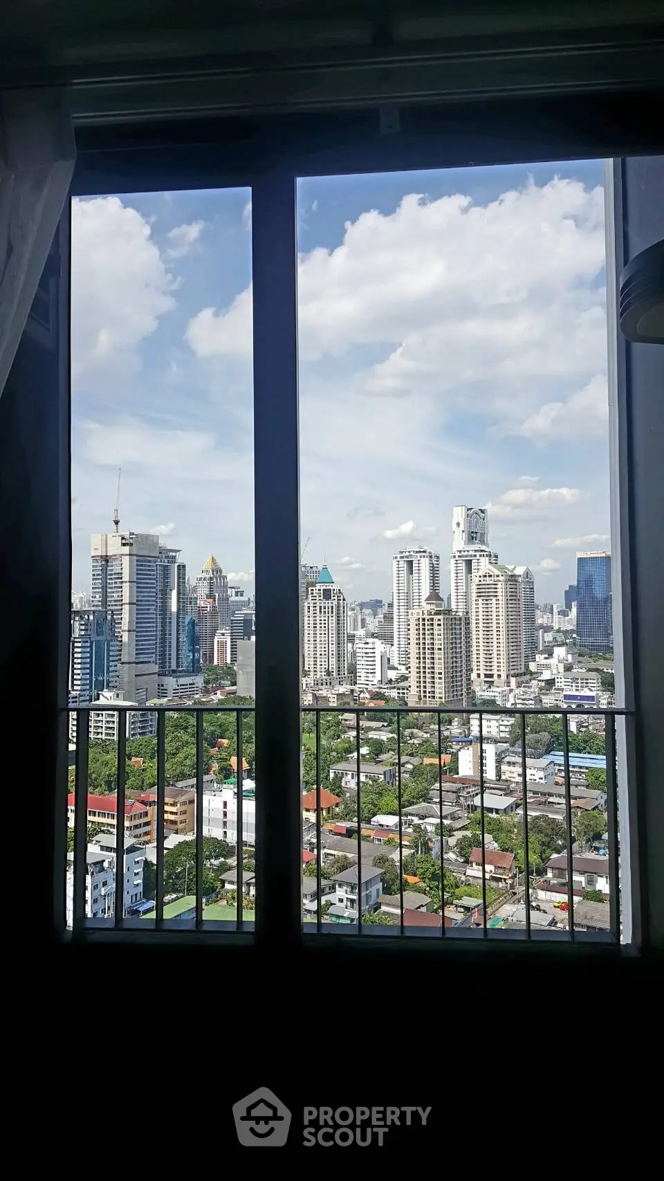 Stunning cityscape view from high-rise apartment window with clear blue sky.