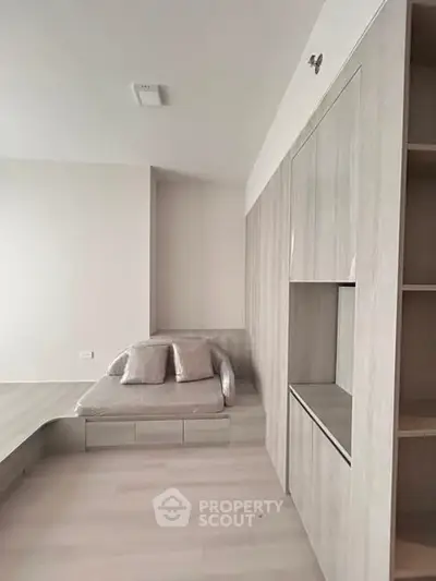 Modern minimalist bedroom with built-in storage and cozy seating area.