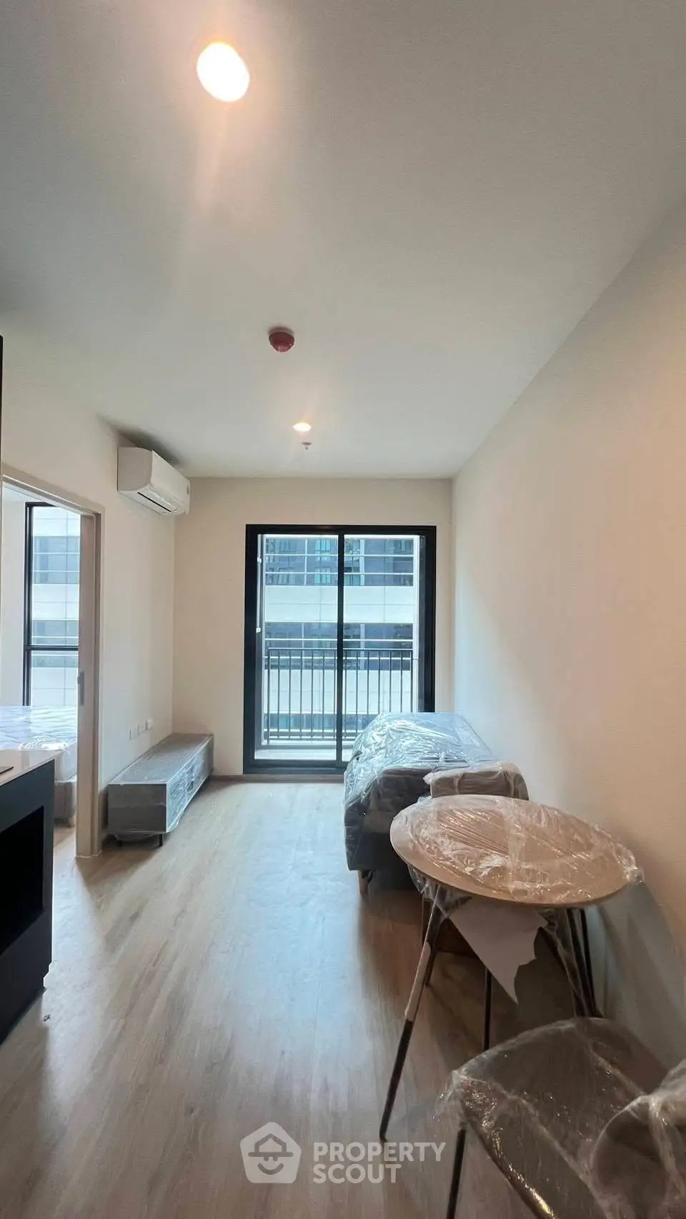 Modern living room with balcony access in a contemporary apartment, featuring sleek furniture and natural light.