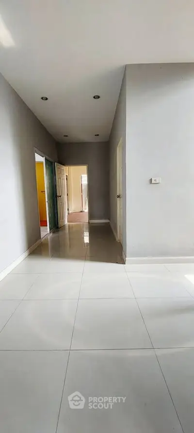 Spacious hallway with glossy tiled flooring and modern recessed lighting.