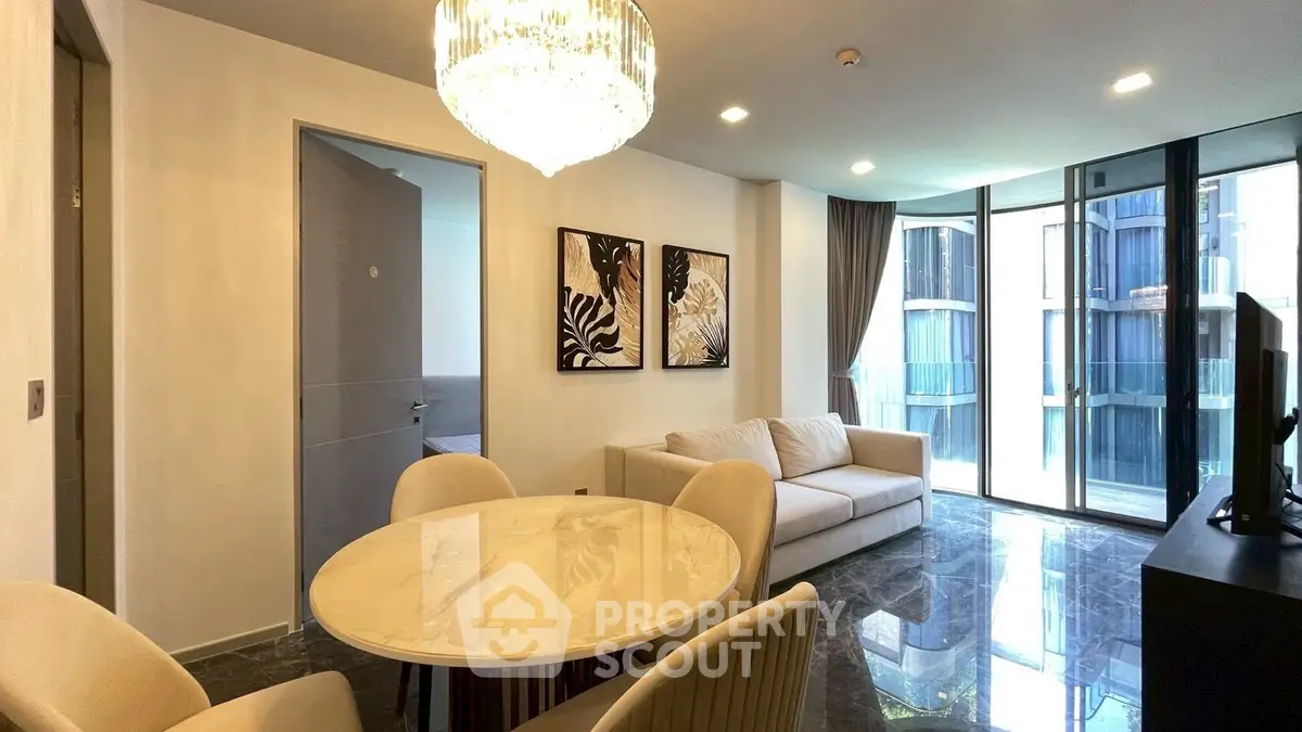 Luxurious modern living room with elegant chandelier and marble flooring in high-rise apartment.