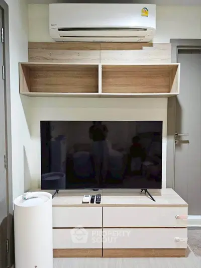 Modern living room with sleek TV setup and air conditioning unit, perfect for cozy entertainment.