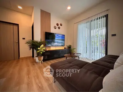 Modern living room with cozy sofa and large TV, featuring stylish decor and natural light.