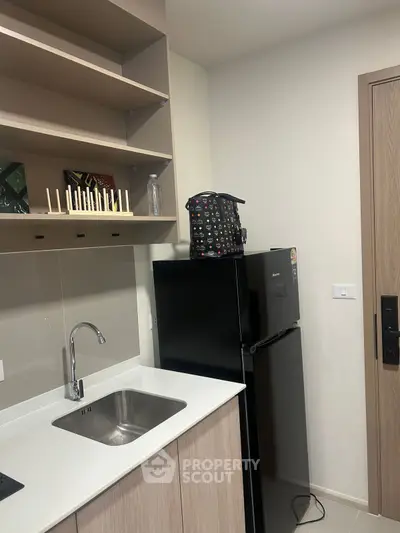 Modern kitchen with sleek cabinetry and compact fridge in a stylish apartment.