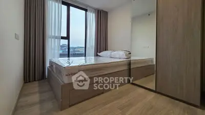 Modern bedroom with large window and wooden flooring in a stylish apartment.