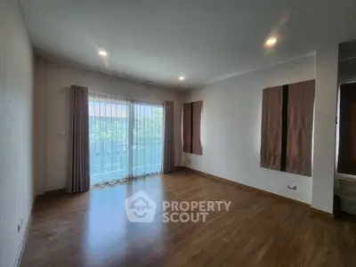 Spacious empty room with large windows and wooden flooring, perfect for customization.