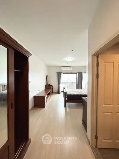 Spacious bedroom with wooden furniture and large window offering natural light.