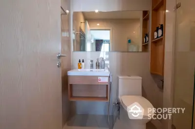 Modern bathroom with sleek fixtures and large mirror in contemporary apartment.