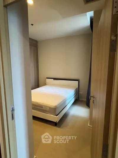 Cozy bedroom with modern bed and wooden flooring in a minimalist apartment.