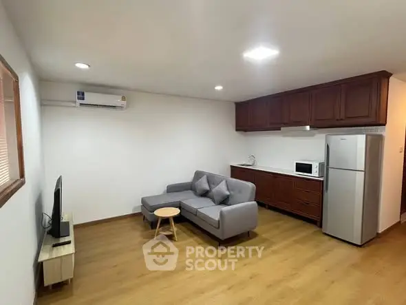 Spacious living room with modern furniture and kitchen appliances in a cozy apartment.