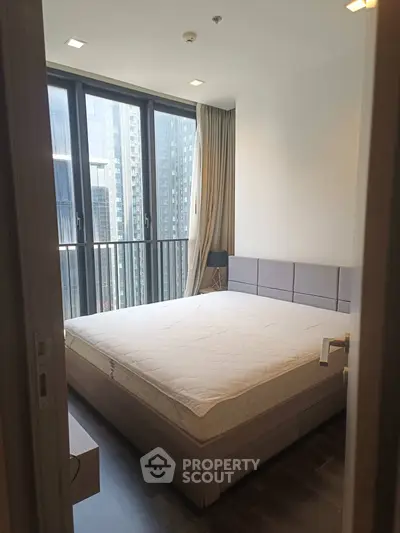 Modern bedroom with large windows and city view in high-rise apartment