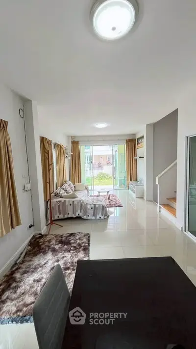 Spacious living room with modern decor and large windows offering natural light and garden view.