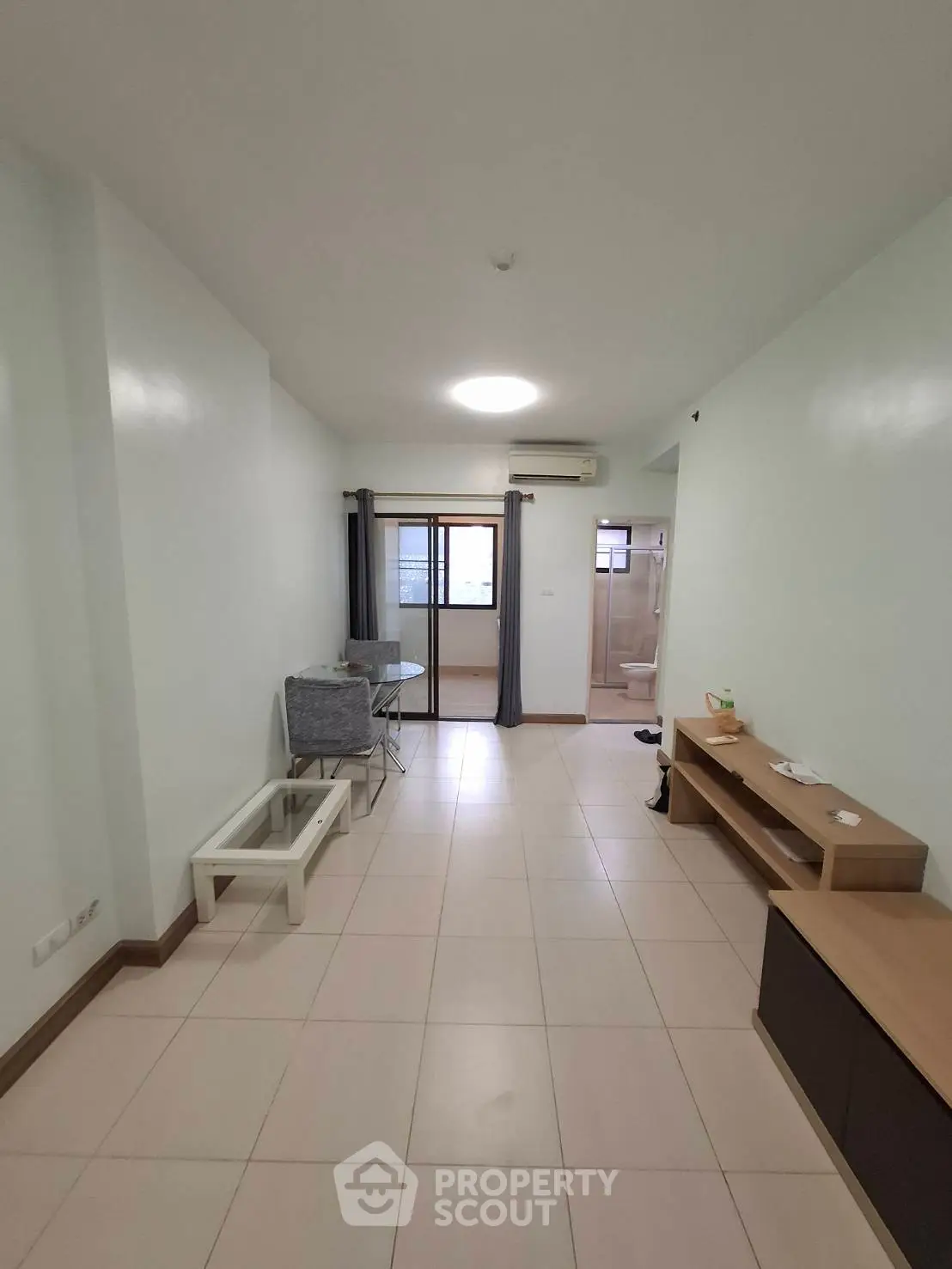 Spacious living room with modern furnishings and balcony access in a minimalist apartment.