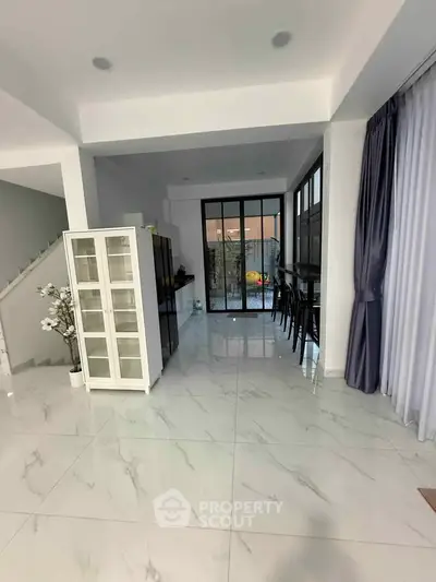 Spacious modern living area with sleek marble flooring and large windows leading to a patio.