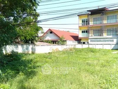 Spacious green plot with potential for development near residential buildings.