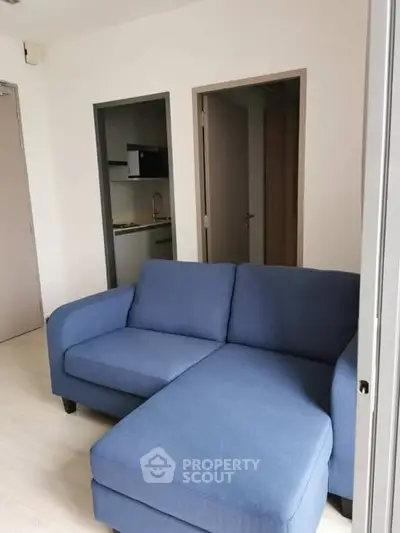 Cozy living room with blue sofa and view into modern kitchen area.