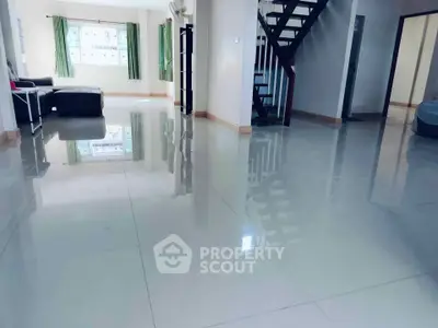 Spacious modern living room with glossy tiled floors and staircase, ideal for family gatherings.