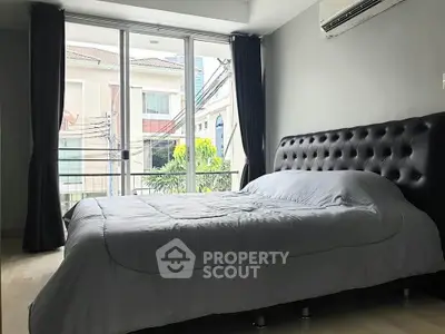 Modern bedroom with large window and stylish bed in a bright apartment.