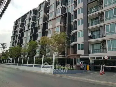 Modern multi-story apartment building with balconies and street view.