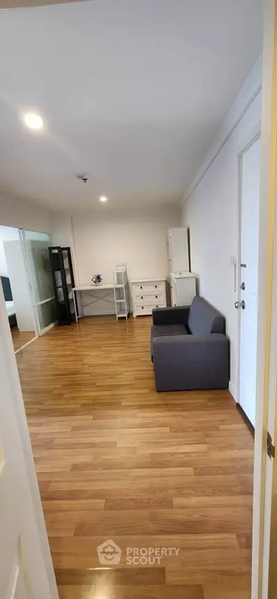 Spacious living room with wooden flooring and modern furniture in a cozy apartment.