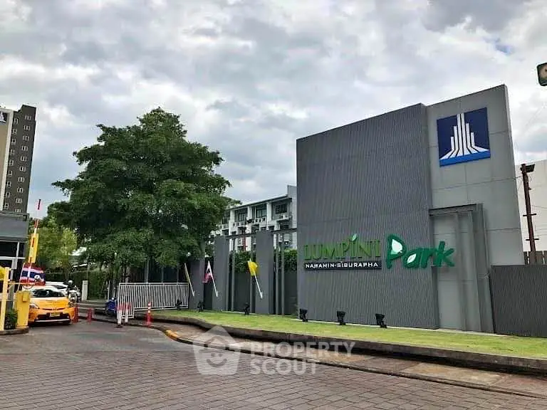 Modern condominium entrance with lush greenery and sleek signage