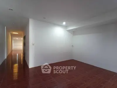 Spacious empty room with wooden flooring and white walls, ideal for customization.