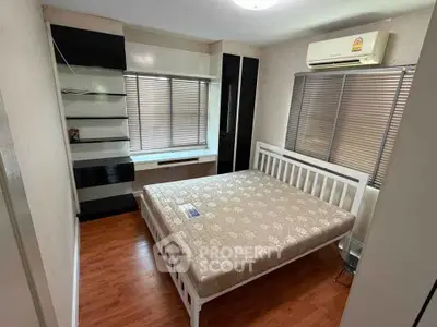 Cozy bedroom with modern furnishings and ample natural light, featuring a comfortable bed and stylish shelving.