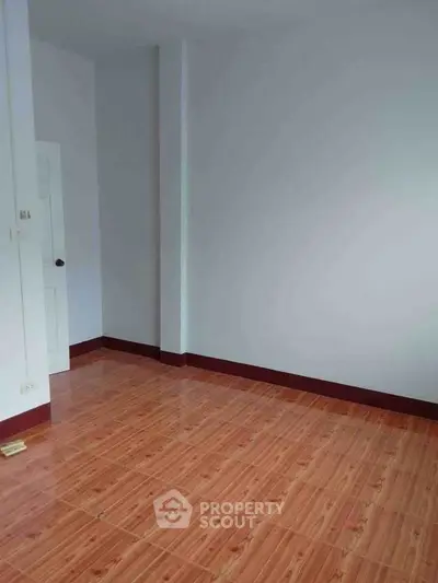 Spacious empty room with wooden flooring and white walls, ideal for customization.