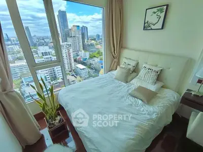Luxurious bedroom with stunning city view from high-rise apartment window.