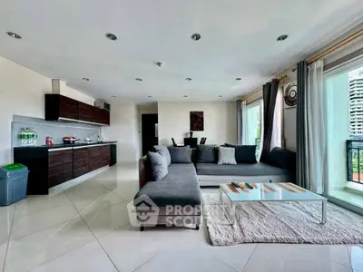 Spacious modern living room with sleek kitchen and large windows offering natural light.