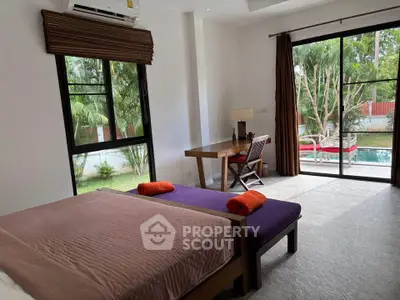 Spacious bedroom with pool view and modern furnishings in a serene setting.