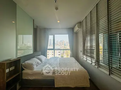 Modern bedroom with city view, featuring large windows and stylish decor.
