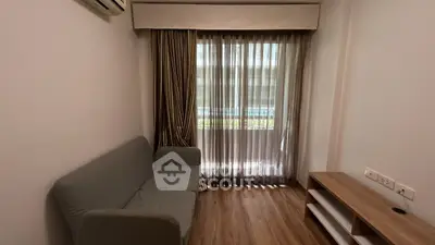 Cozy living room with modern sofa and natural light through sheer curtains.