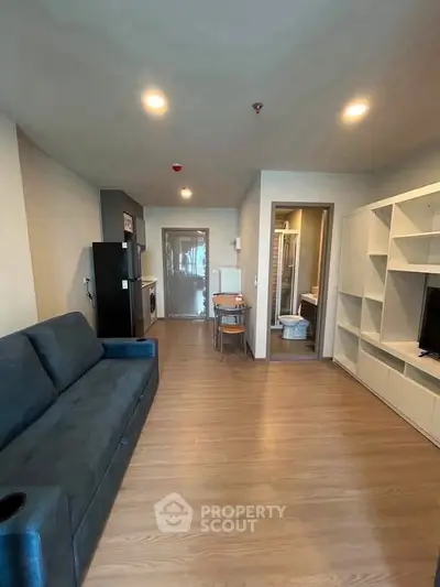Modern living room with sleek furniture and open layout, featuring a cozy sofa and stylish shelving.