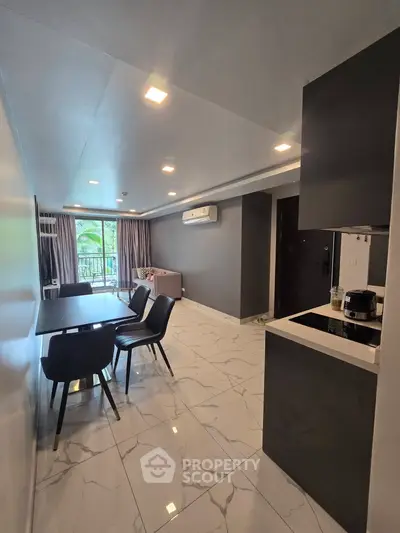 Modern open-layout living room with sleek kitchen and dining area, featuring elegant marble flooring and natural light.